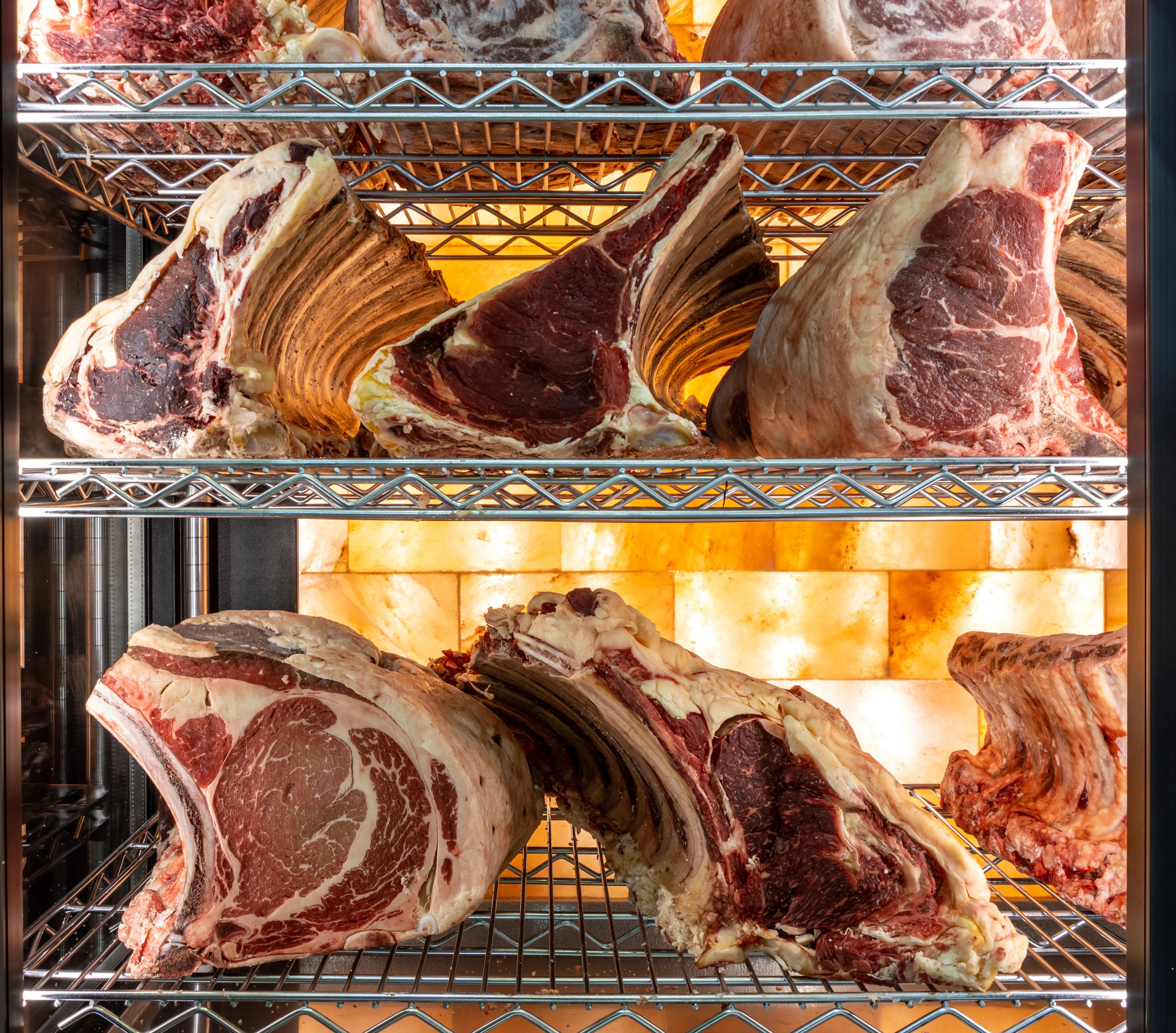 Zu sehen ist Dry Aged Beef in der Reifekammer vor einer Salzwand